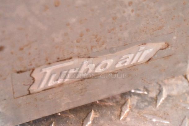 "Turbo Air" logo on metal surface, part of mobile kitchen trailer equipment, indicates brand of refrigeration unit.