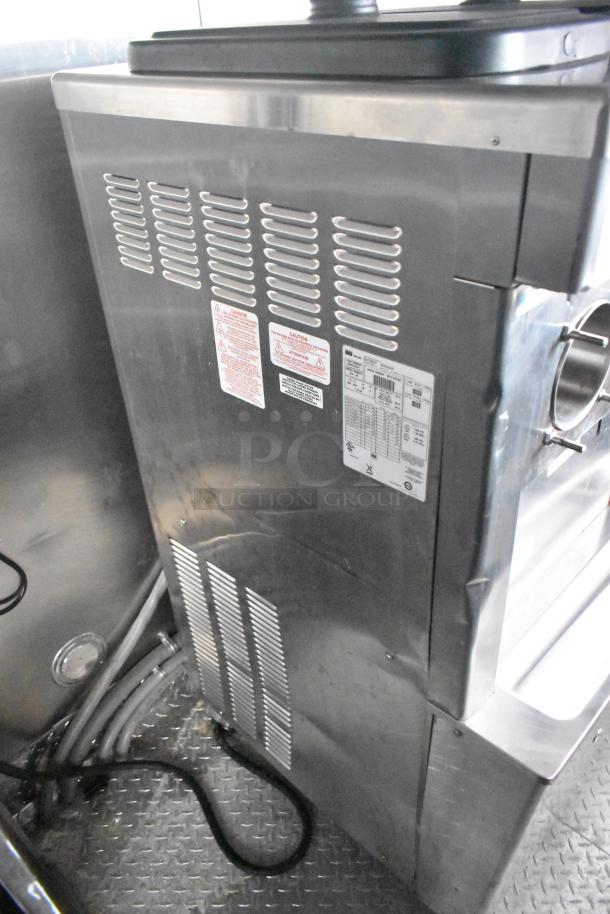 Stainless steel panel of a Henny Penny Evolution Elite 3-Bay Gas Fryer inside a mobile kitchen trailer, showing labels and ventilation.