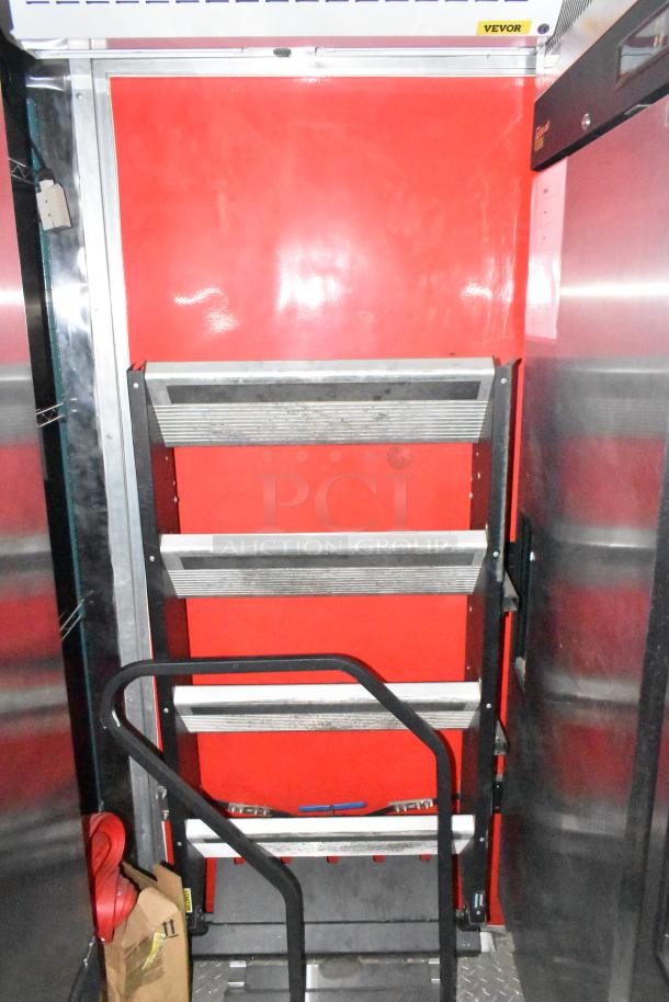 Interior of a brand new Wendy's mobile kitchen trailer featuring shelves and equipment. Bright red and stainless steel details.