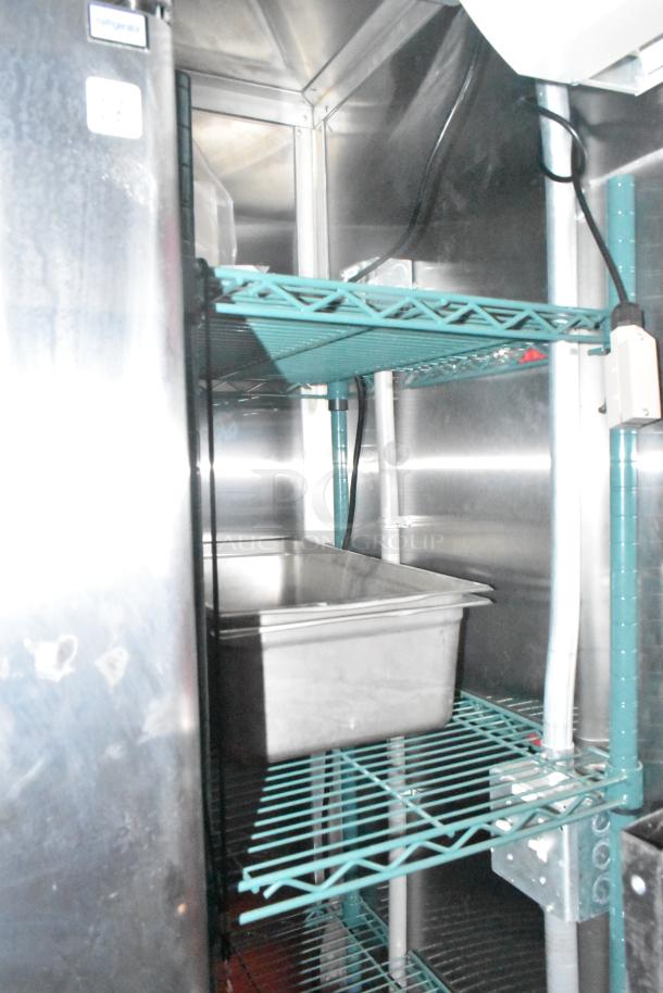 Interior view of a new Wendy's mobile kitchen trailer with stacked metal shelves, stainless steel pan, and visible wiring.