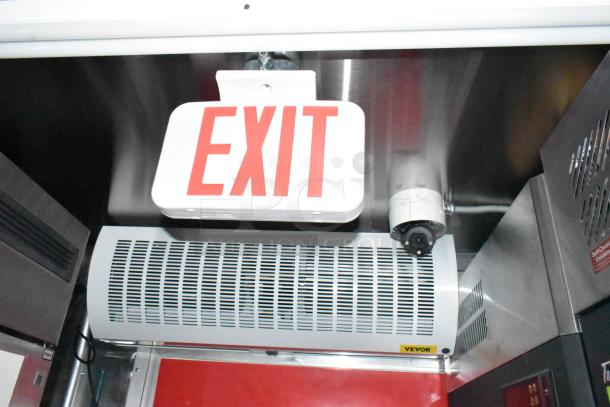 Interior view of Wendy's mobile kitchen trailer showing an exit sign, ventilation unit labeled "Vevor," and surveillance camera.