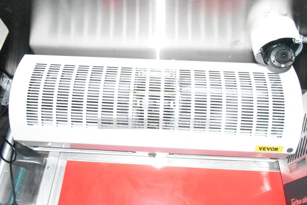 Vevor air curtain in new condition, mounted above stainless steel surface, features ventilation grill and visible security camera.