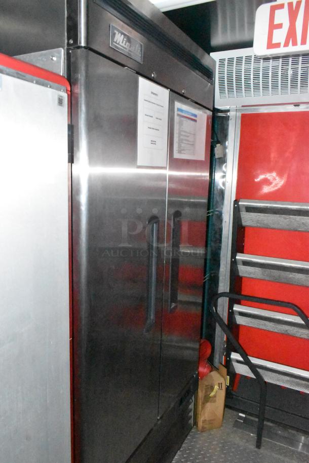 Stainless steel refrigerator inside Wendy's mobile kitchen trailer, featuring visible signage and shelving.