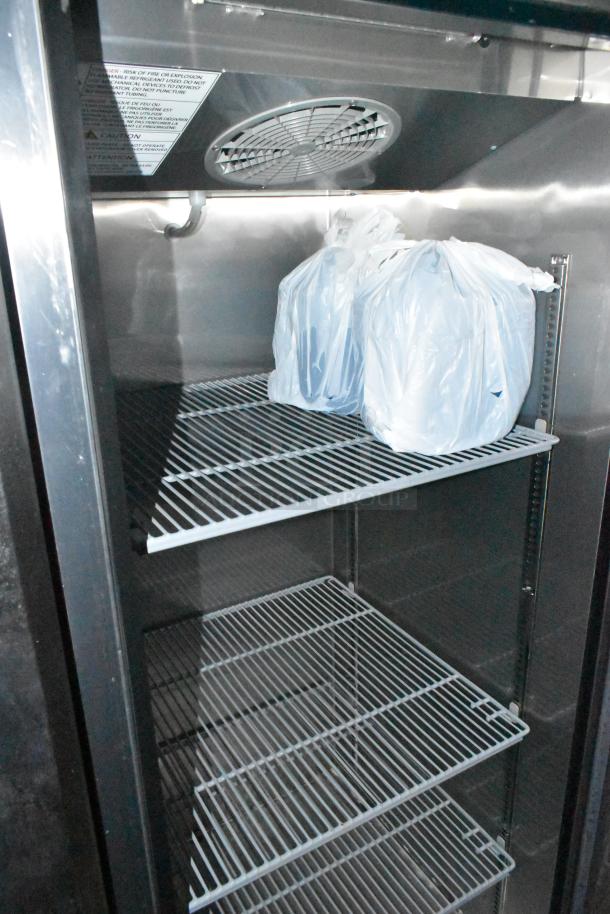 Interior view of a new refrigeration unit in a mobile kitchen trailer, with shelves and plastic-wrapped items.