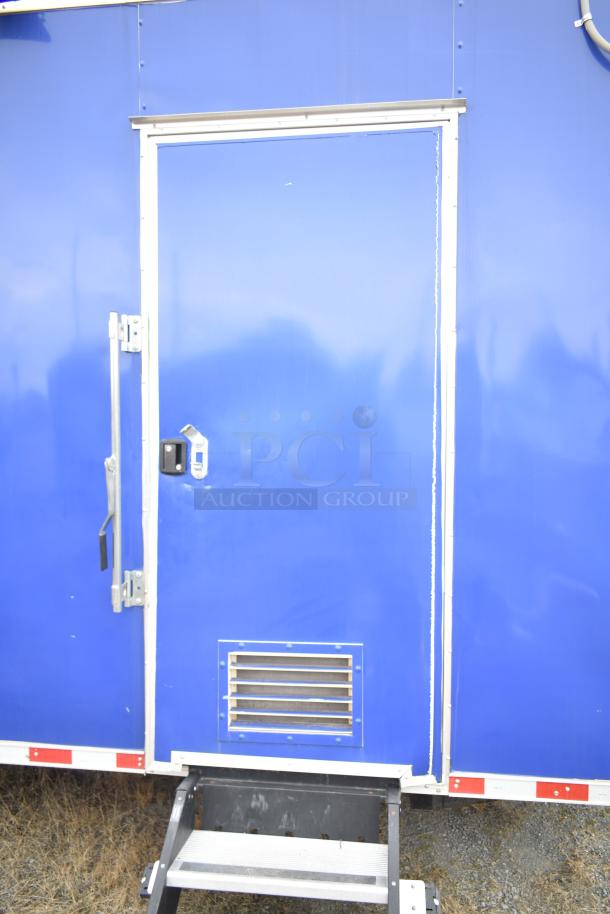 Blue 2021 Rock Solid Cargo 28' fast food trailer, metal door with handle, vent, and steps visible.