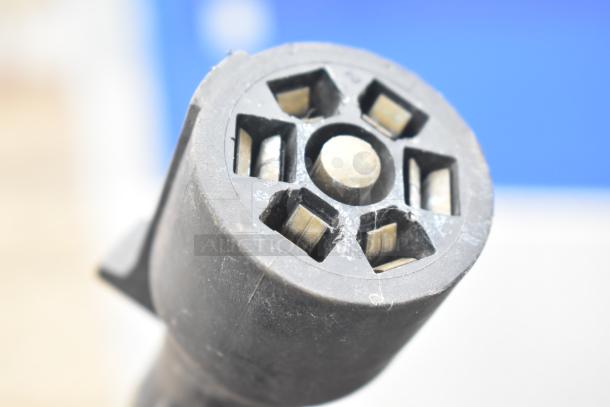 Close-up of a circular, black, multi-pin trailer connector plug.
