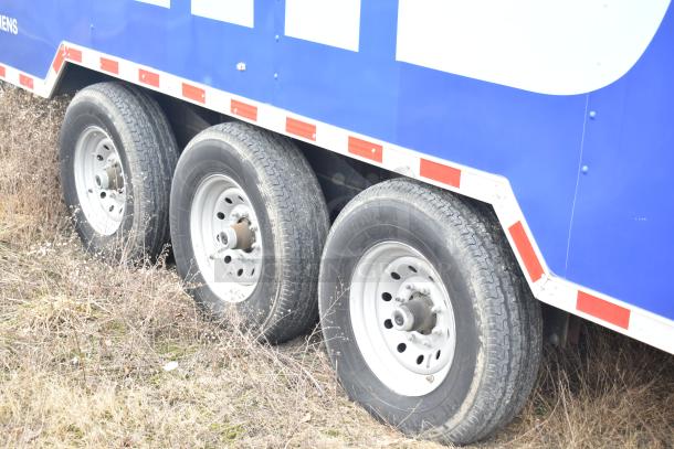 Rock Solid Cargo 28’ trailer wheels and lower body with blue exterior and red reflective trim.