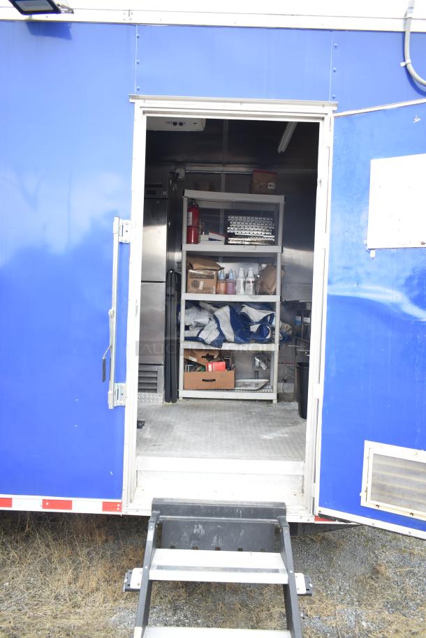 Blue 2021 Rock Solid Cargo 28' mobile kitchen trailer interior, showing shelves with supplies. Ready for use.