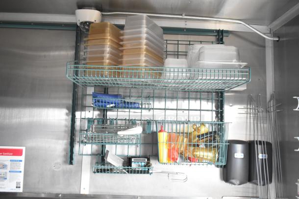 2021 Rock Solid Cargo mobile kitchen interior with shelving holding food containers and condiments. Clean setup with commercial equipment.