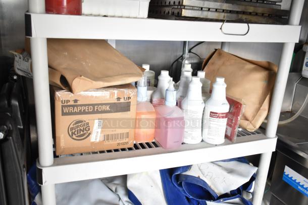 Burger King supplies in a mobile kitchen. Includes labeled boxes, cleaning bottles, and storage shelves. Perfect for fast food operations.
