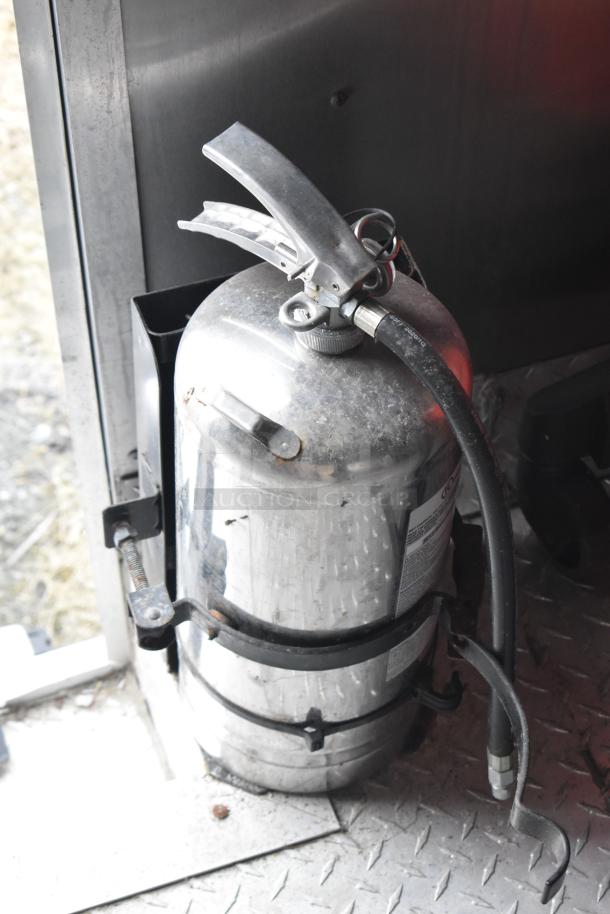Metal fire extinguisher mounted inside the Rock Solid Cargo mobile kitchen trailer.