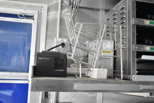 Interior of a 2021 Rock Solid Cargo fast food trailer showing commercial kitchen equipment including a Star TSP100III printer and metal rack, set against a stainless steel wall.