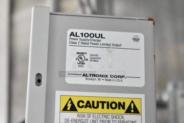 Power supply/charger AL100UL label showing Class 2 rated output, UL listed, made by Altronix Corp in the USA, with caution sign.