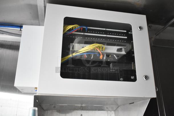 Networking equipment in a metal enclosure with cables and CyberPower unit inside a Rock Solid Cargo trailer.