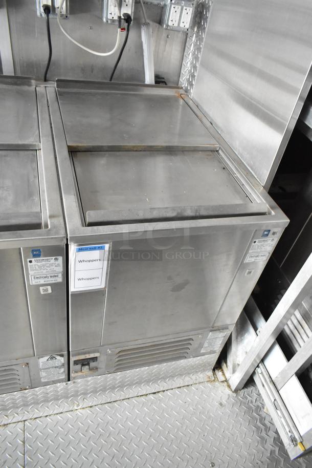 Stainless steel industrial kitchen appliances inside a mobile kitchen trailer with visible labels indicating "Whoppers."