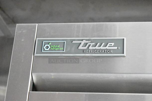 Close-up of True Refrigerator logo with "natural refrigerant" label on stainless steel surface, indicating eco-friendly design.