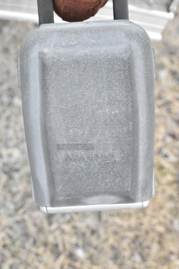 Gray Master Lock padlock on a metal latch, showing signs of wear.