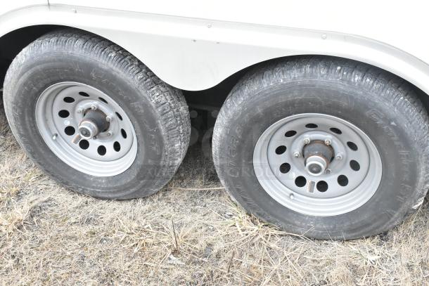 Dual tires of a 2020 ATX 8.5' x 24' cold food trailer, showing durable tread on grass surface.