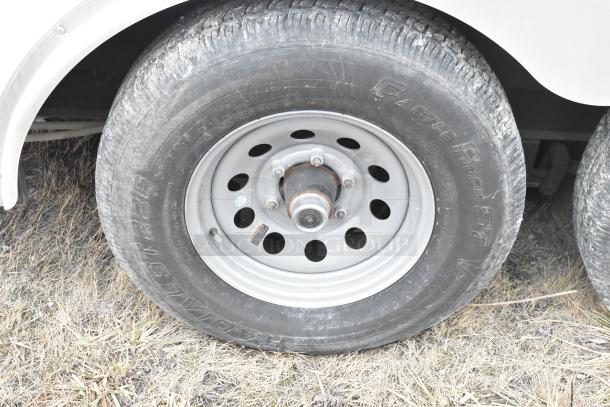 Close-up of the wheel of an ATX 8.5' x 24' single axle trailer, showing a steel rim and Castle Rock ST radial tire in fair condition.