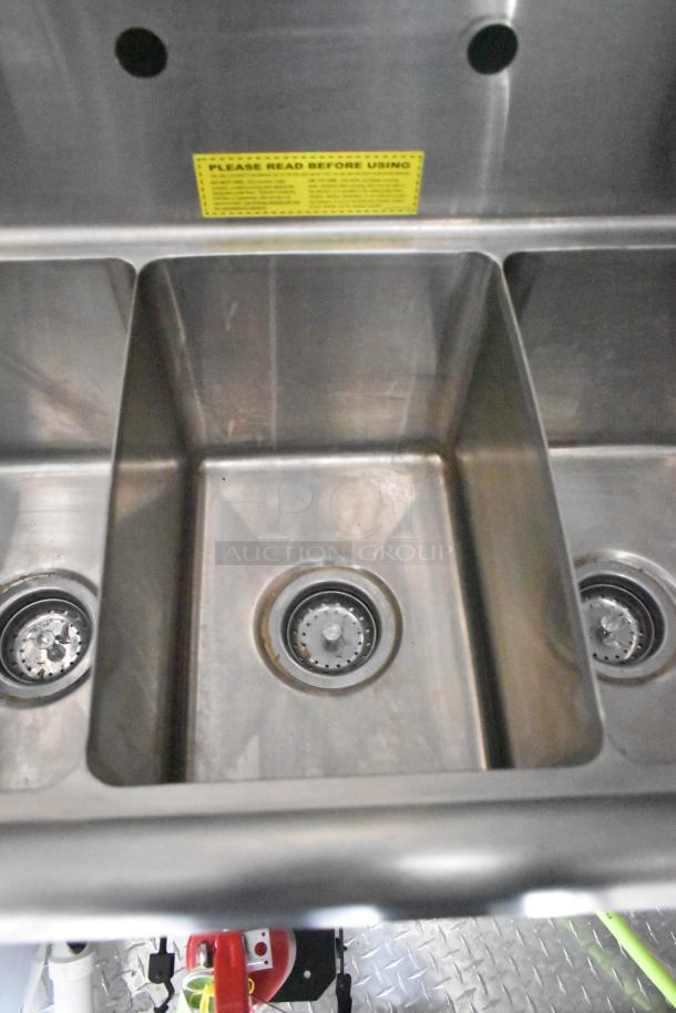 Stainless steel triple sink in 2020 ATX 8.5' x 24' food trailer with visible usage instructions label above sinks.