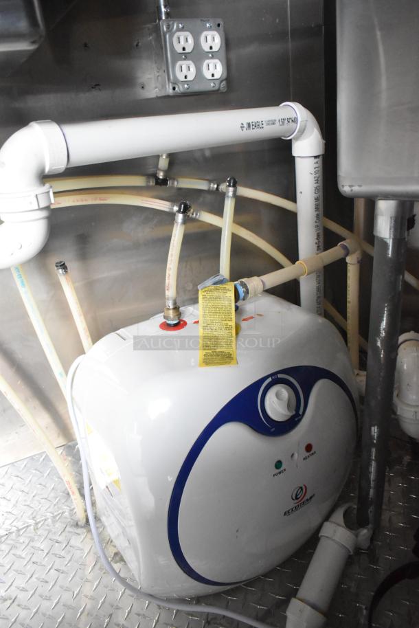 Inside view of plumbing and Ecotemp water heater in a 2020 ATX food trailer, featuring connected pipes and outlets.