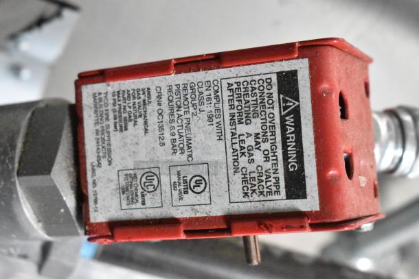 Red valve actuator with safety warning, compliance info, and ULC certification for ATX trailer's fire suppression system.