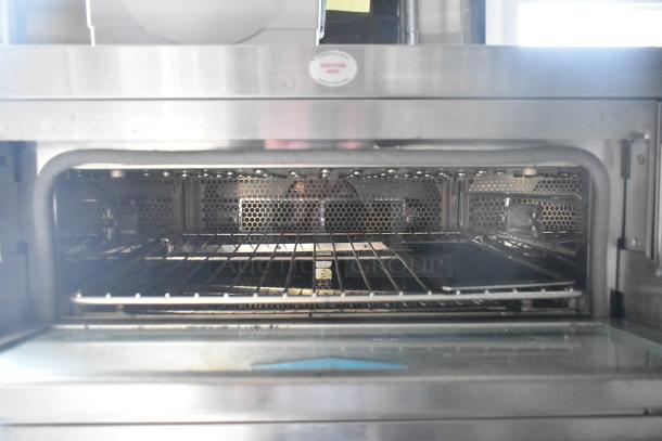 Interior view of a stainless steel oven in a 2020 ATX 8.5' x 24' food trailer, featuring wire racks and a hexagonal vent pattern.