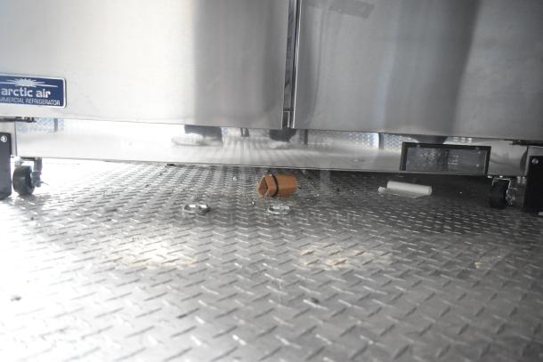 2020 ATX Cold Food Trailer interior, featuring Arctic Air refrigerator on a diamond-plate floor. Visible logo, minor debris present.