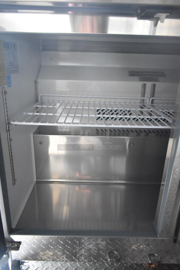 Interior of 2020 ATX food trailer with empty Arctic Air cooler. Features a steel wire shelf and diamond plate floor.