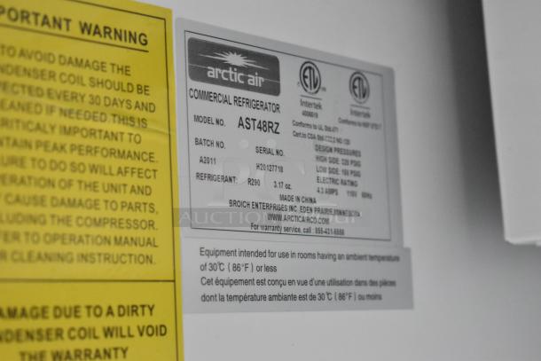 Arctic Air commercial refrigerator label showing model AST48RZ, batch A2011, refrigerant details, and manufacturer info.