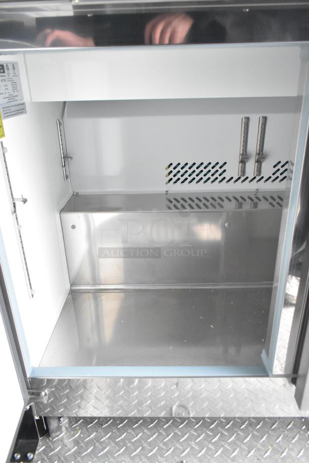 Interior view of ATX 8.5' x 24' food trailer, featuring shiny metal storage compartment and diamond plate flooring.