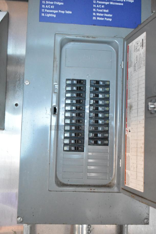 Control panel of 2019 Cruising Kitchens trailer, labeled switches for electrical systems, partially open cover showing breakers.