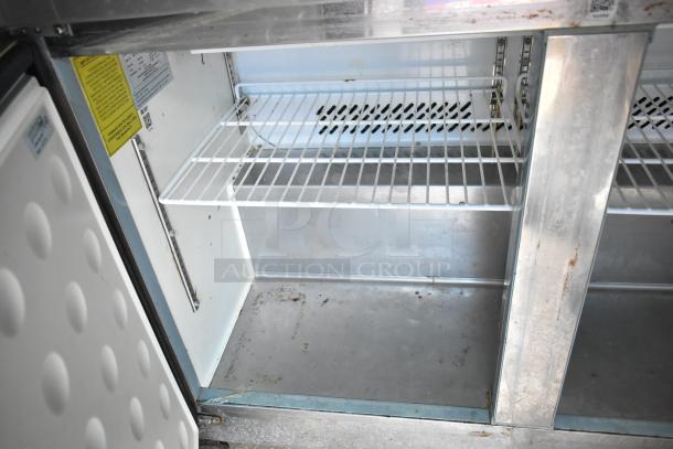 Interior of Arctic Air cooler from 2019 Cruising Kitchens trailer, featuring wire shelving. Visible wear and minor dirt present.