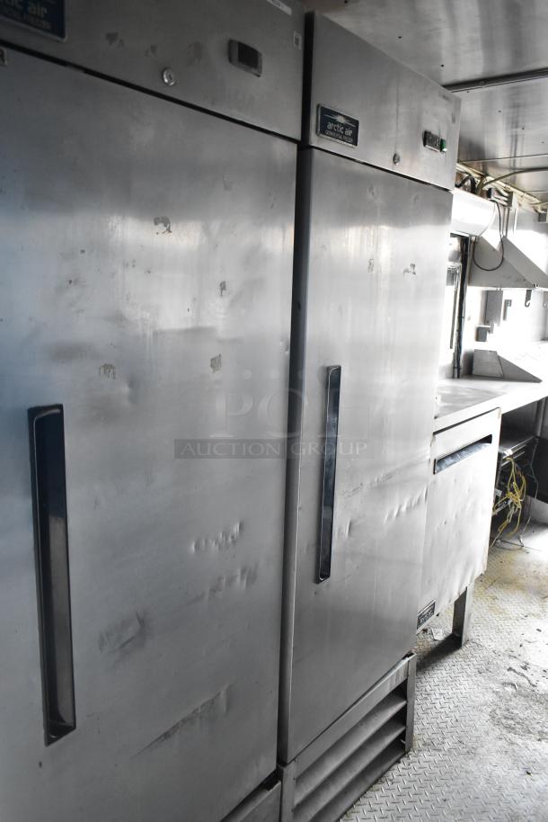 Cruising Kitchens trailer interior with Arctic Air refrigerators, visible wear, and stainless steel surfaces.