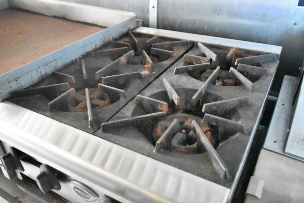 Four-burner stove in the 2019 Cruising Kitchens cold food trailer, featuring visible wear. Equipped with a CaptiveAire grease hood.