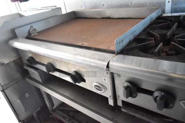Interior of 2019 Cruising Kitchens trailer showing a Wells griddle and stove, featuring control knobs and stainless steel design.