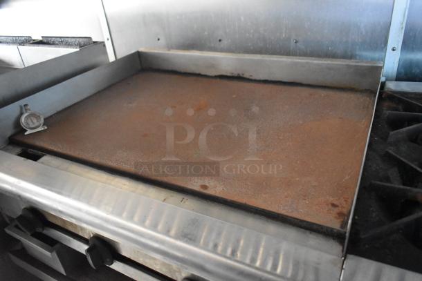 2019 Cruising Kitchens food trailer's griddle, rusted surface, with temperature gauge, indoor kitchen setting.