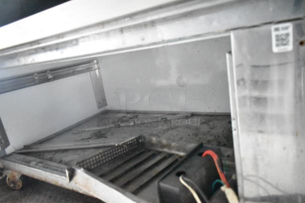 Interior view of 2019 Cruising Kitchens cold food trailer, showing wheels and metal components. Features grease hood, fire suppression, and Arctic Air appliances.