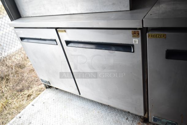 2019 Cruising Kitchens trailer interior with Arctic Air coolers, visible grease hood, and diamond plate flooring, in used condition.