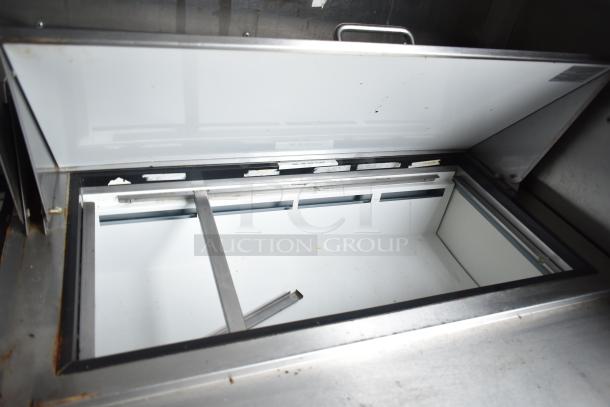 Open interior view of Arctic Air cooler in 2019 Cruising Kitchens food trailer, featuring stainless steel frame and clean surface.