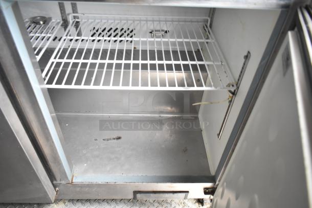 Interior view of an Arctic Air cooler inside a 2019 Cruising Kitchens 8.5' x 24' trailer, showing metal shelves and slight wear.