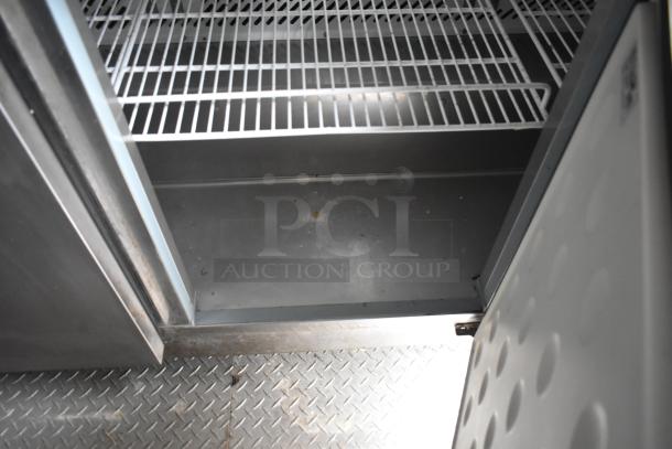 Interior of 2019 Cruising Kitchens trailer showing metal shelving, diamond plate floor, highlighting storage space.