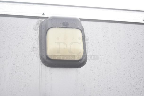 Close-up of a light fixture on the exterior of a 2021 Nationwide 8.5' x 24' food trailer shell, shown with raindrops.