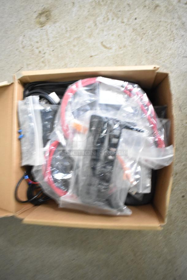 Box of assorted cables and components, including red and black wiring, packaged neatly in plastic bags within a cardboard box.