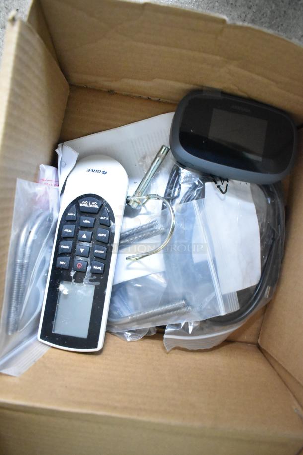 Cardboard box with electronics, a remote labeled "Gree," and various cables.