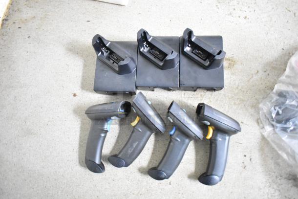 Four barcode scanners with black charging docks on a concrete surface, suitable for inventory systems.