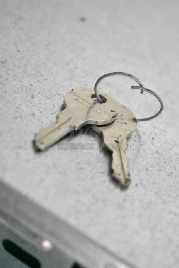 Close-up of two keys on a ring, resting on a surface, related to a 2021 Nationwide 8.5' x 24' food trailer shell.