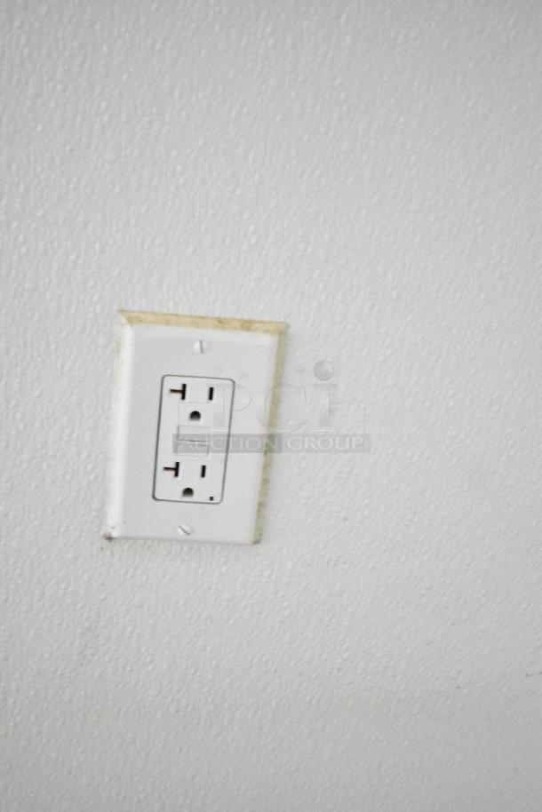 White electrical outlet on a textured wall, standard two-prong and three-prong sockets, slightly worn edges.