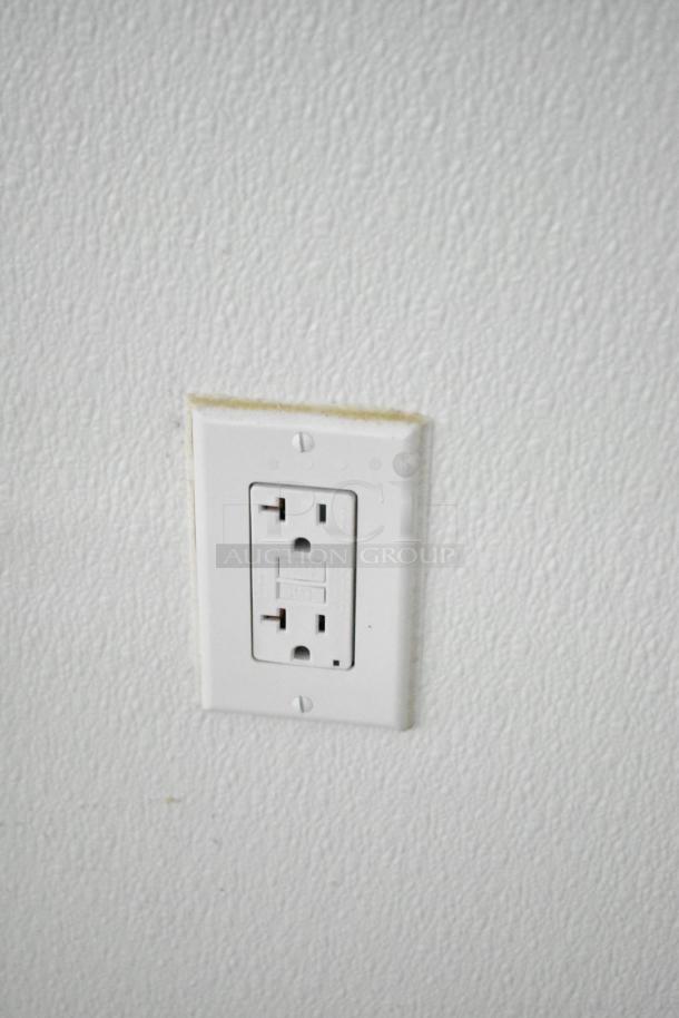 Close-up of an electrical outlet on a white, textured wall inside a 2021 Nationwide food trailer shell.