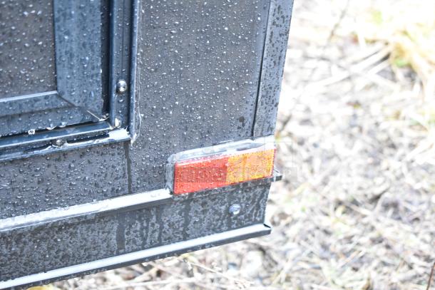 2020 SDG 8.5' x 20' food trailer shell, black exterior with visible reflectors, rain droplets on surface. Ready to equip.